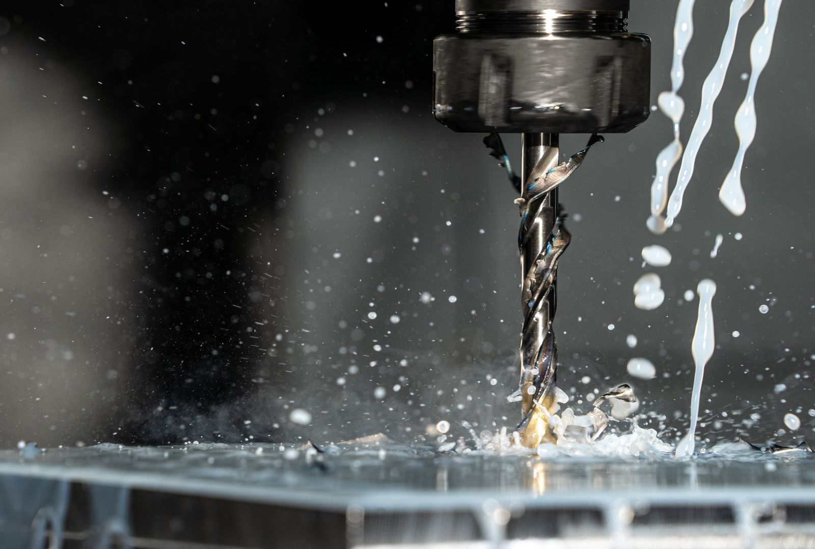 Bohrer einer CNC-Maschine mit Kühlmittel beim Bohren in ein Werkstück (Symbolfoto)