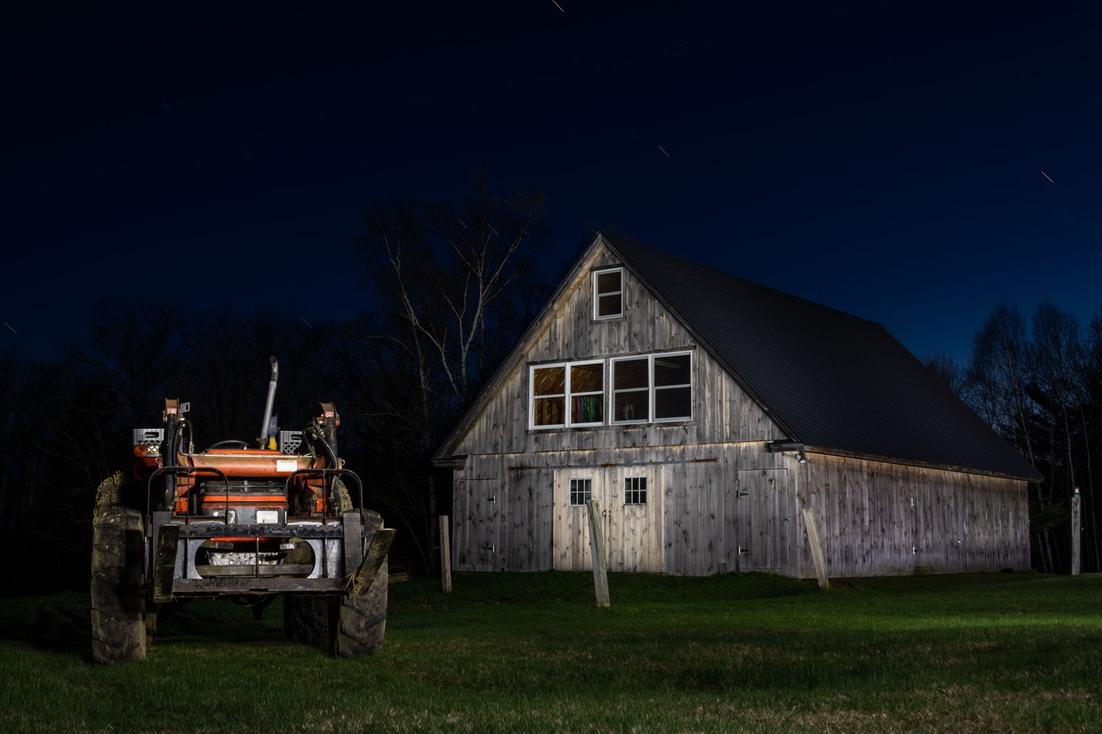Traktor mit Frontanbau bei Nacht vor einer Scheune (Symbolfoto)