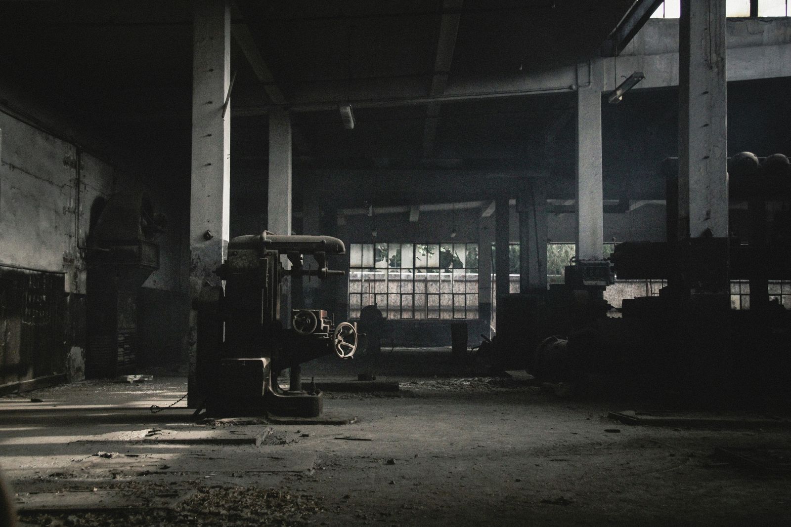 Dunkle Industriehalle mit historischer Bohrmaschine im Gegenlicht (Symbolfoto)