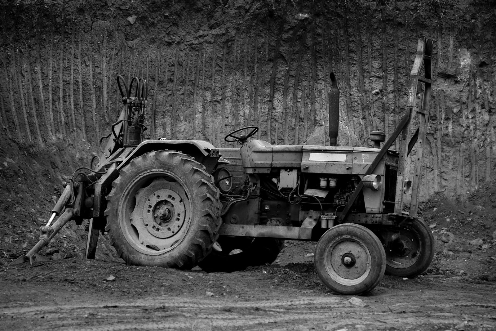 Alter Traktor mit Heckbagger-Anbau, Schwarzweiß (Symbolfoto)